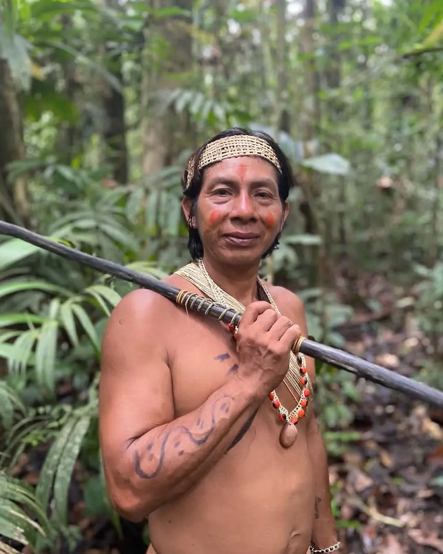 Guía waorani con corona tejida sosteniendo una cerbatana en el bosque de Shiripuno