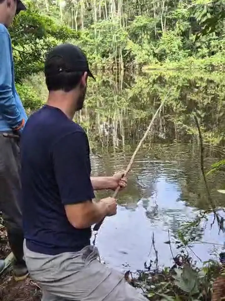 Visitante pescando pirañas con caña artesanal en una laguna del Shiripuno